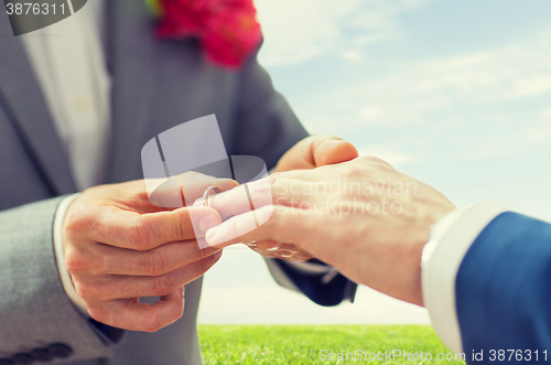 Image of close up of male gay couple hands and wedding ring