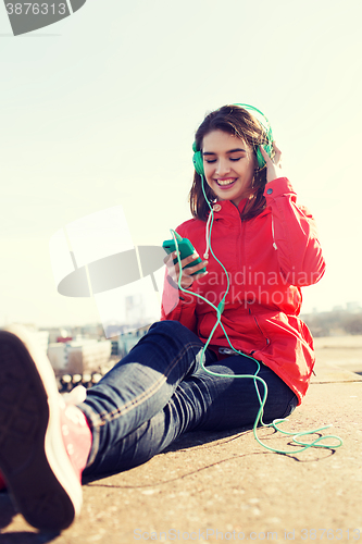 Image of happy young woman with smartphone and headphones