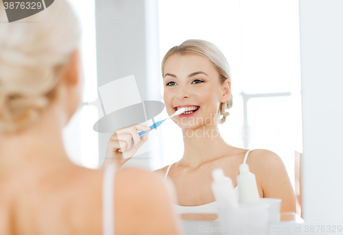Image of woman with toothbrush cleaning teeth at bathroom