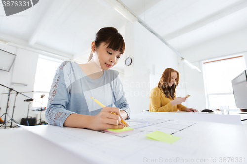 Image of architect woman with blueprint writing at office