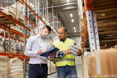 Image of worker and businessmen with clipboard at warehouse