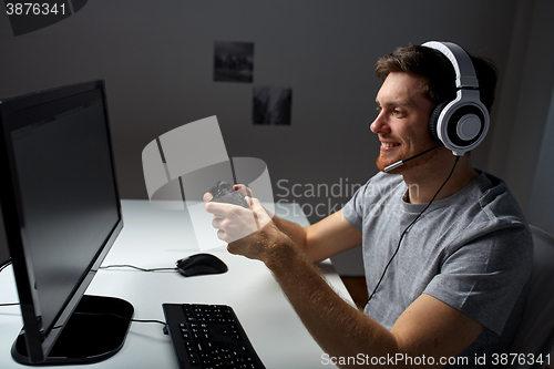 Image of man in headset playing computer video game at home