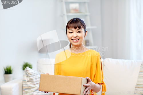 Image of happy asian young woman with parcel box at home