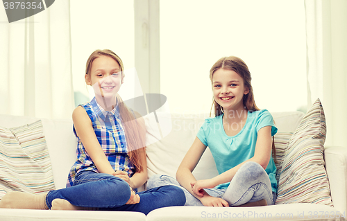 Image of happy little girls sitting on sofa at home