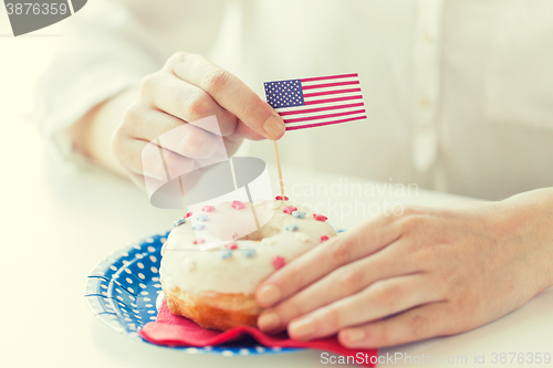 Image of female hands decorating donut with american flag