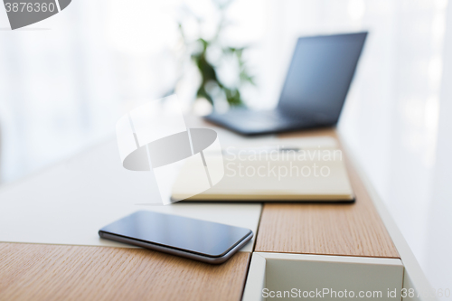 Image of notebook, laptop and smartphone on office table