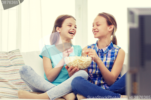 Image of happy girls with popcorn watching tv at home