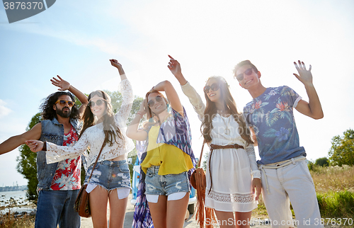 Image of happy young hippie friends dancing outdoors