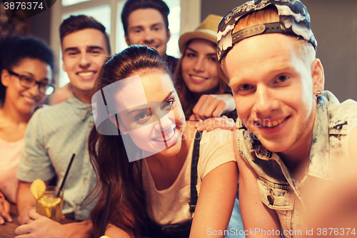 Image of happy friends with smartphone taking selfie at bar