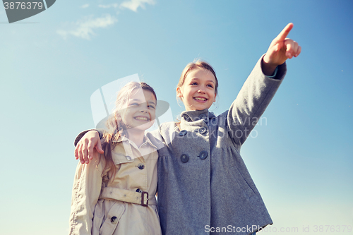 Image of happy little girls hugging and pointing finger