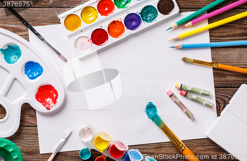 Image of Paper, watercolors, paint brush and some art stuff on wooden   table