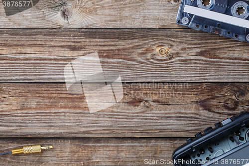 Image of Cassette tape, cassette player and headphones over wooden table. top view.