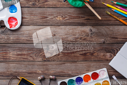 Image of Paper, watercolors, paint brush and some art stuff on wooden   table