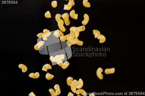 Image of Falling gobetti pasta. Flying yellow raw macaroni over black background. 