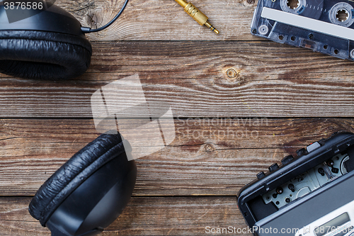 Image of Cassette tapes, cassette player and headphones over wooden table. top view.