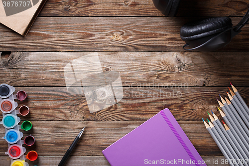 Image of Watercolors, color pencils and sketchbook on wooden table. Flat lay photo with empty space for logo, text.