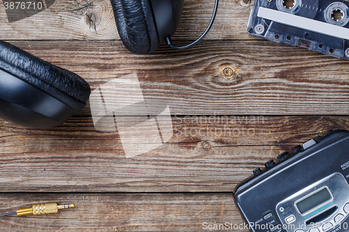 Image of Cassette tapes, cassette player and headphones over wooden table. top view.