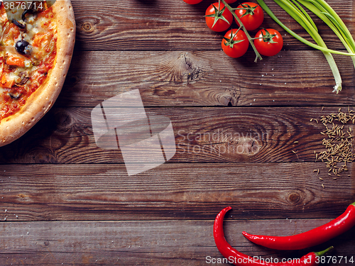 Image of Italian pizza with tomatoes on a wooden table, top view.