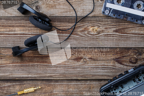 Image of Cassette tape, cassette player and headphones over wooden table. top view.