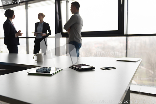 Image of close up of tablet, business people on meeting in background