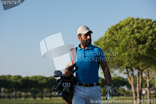 Image of golfer  walking and carrying bag