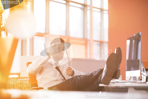 Image of relaxed young businessman first at workplace at early morning