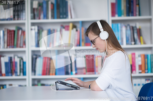 Image of female student study in library, using tablet and searching for 