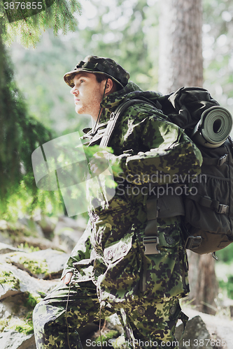 Image of young soldier with backpack in forest
