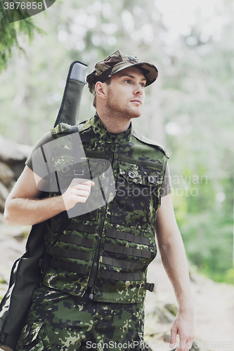 Image of young soldier or hunter with gun in forest