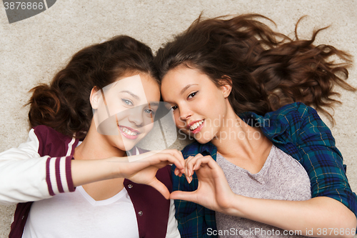 Image of happy smiling pretty teenage girls lying on floor