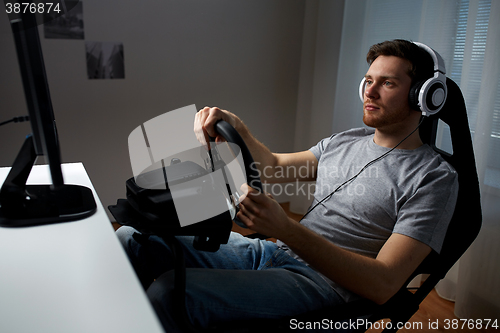 Image of man playing car racing video game at home