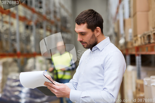 Image of businessman writing to clipboard at warehouse