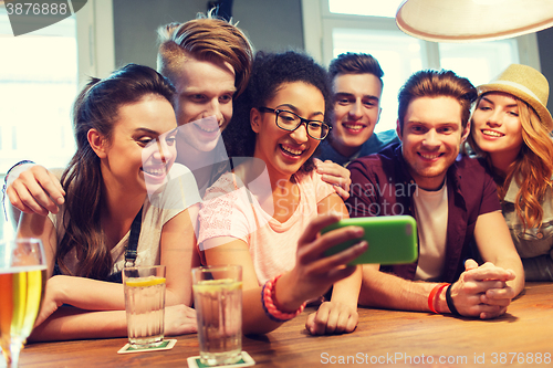 Image of happy friends with smartphone taking selfie at bar