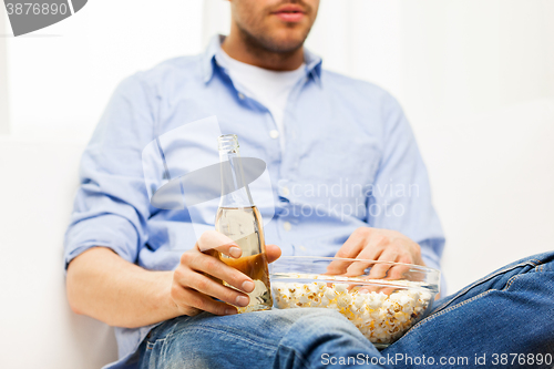 Image of close up of man with popcorn and beer at home