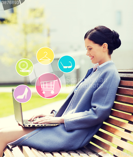 Image of smiling business woman with laptop in city