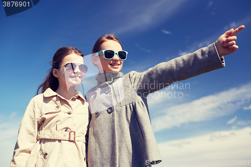 Image of happy little girls hugging and pointing finger