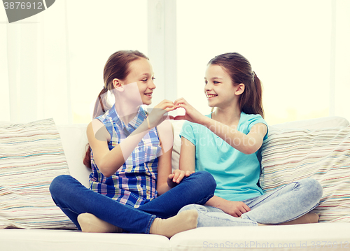 Image of happy little girls showing heart shape hand sign