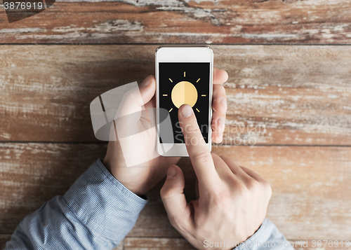 Image of close up of hands with sun icon on smartphone