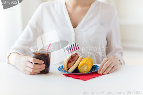 Image of close up of woman eating hot dog with cola