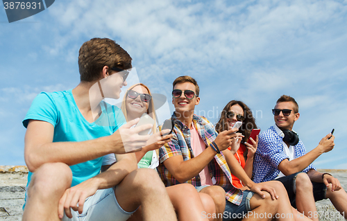 Image of group of happy friends with smartphones outdoors