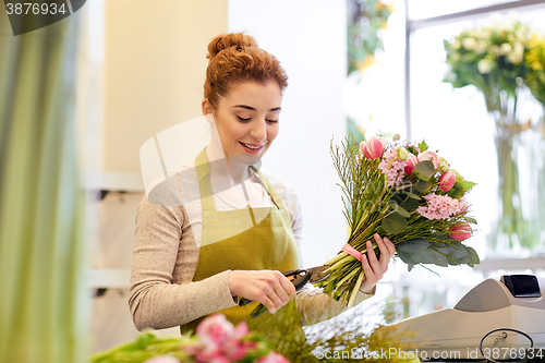 Image of smiling florist woman making bunch at flower shop