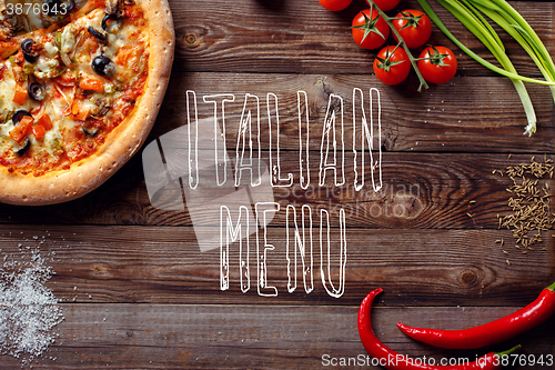 Image of Italian pizza with tomatoes on a wooden table, top view, close-up