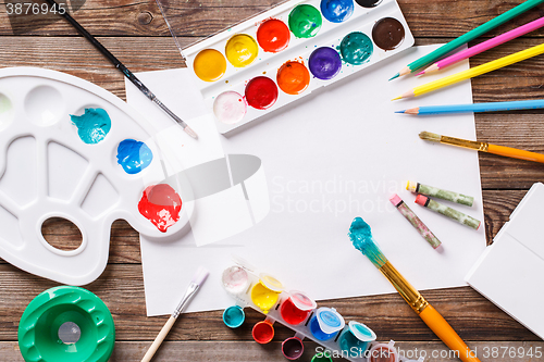 Image of Paper, watercolors, paint brush and some art stuff on wooden   table