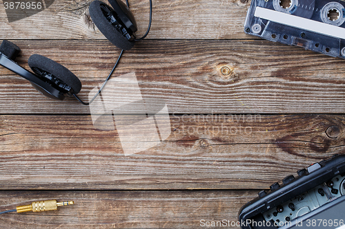 Image of Cassette tape, cassette player and headphones over wooden table. top view.