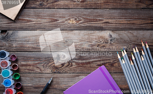 Image of Watercolors, color pencils and sketchbook on wooden table. Flat lay photo with empty space for logo, text.