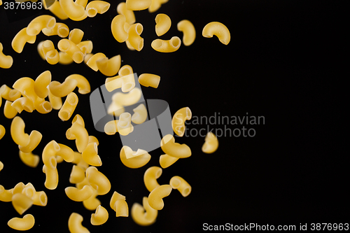 Image of Falling gobetti pasta. Flying yellow raw macaroni over black background. 