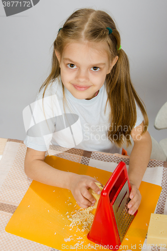 Image of The little girl at the table t grated cheese