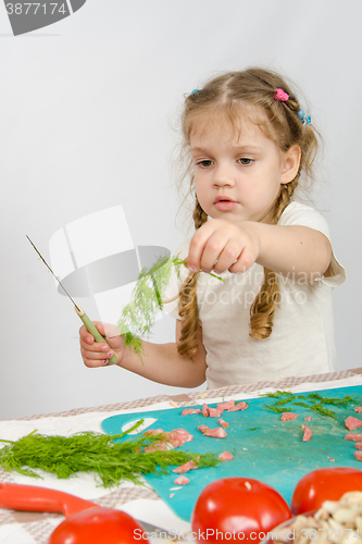 Image of Little six year old girl looking at sprig of parsley is holding in his hand