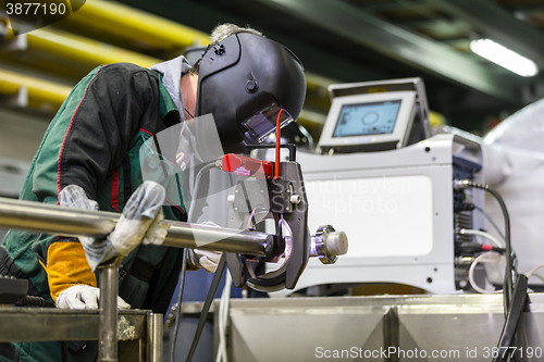 Image of Industrial worker setting orbital welding machine.