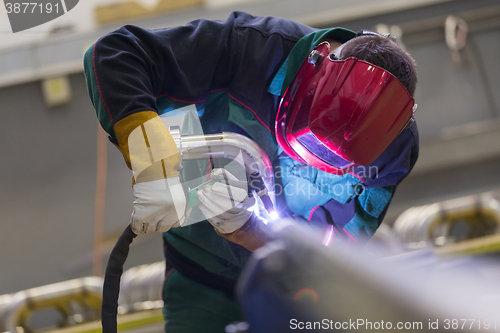 Image of Industrial worker welding in metal factory.